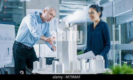 Due professionale maschio e femmina ingegneri architettonico lavorare con Blueprint e su un modello di edificio di design per la pianificazione urbana progetto. Foto Stock