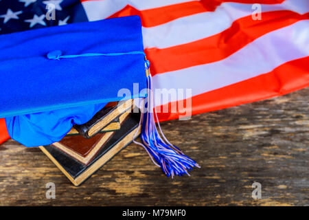 Scuola americana di graduazione graduazione blu hat su libri con bandiera americana sfondo Foto Stock