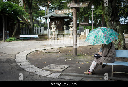 Donna con ombrello verde appoggiata nel parco, Kawagoe Saitama, Giappone Foto Stock