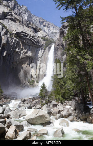 Colore diurno foto verticale di Yosemite Falls nel Parco Nazionale di Yosemite in California, Stati Uniti d'America. Leggera acqua turchese e massi in primo piano. Foto Stock