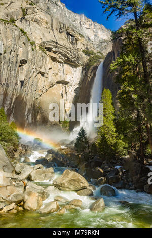 Colore diurno foto verticale di Yosemite Falls nel Parco Nazionale di Yosemite in California, Stati Uniti d'America. Vi è un arcobaleno metà di terra alla base delle cascate. Foto Stock