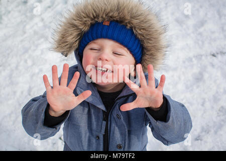 Giovane ragazzo giocare nella neve nel loro giardino sul retro Foto Stock