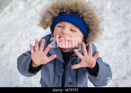 Giovane ragazzo giocare nella neve nel loro giardino sul retro Foto Stock