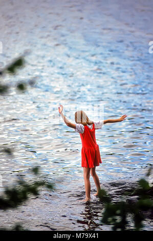 Una giovane ragazza in un abito rosso al Summer Camp salse la sua dita dei piedi in acqua fredda di un lago vicino al suo campeggio. Foto Stock