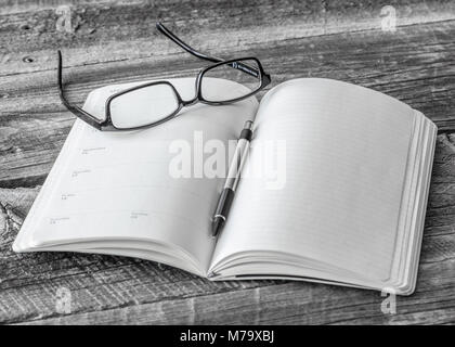 Plain Notebook e matita con un paio di occhiali sul tavolo di legno Foto Stock