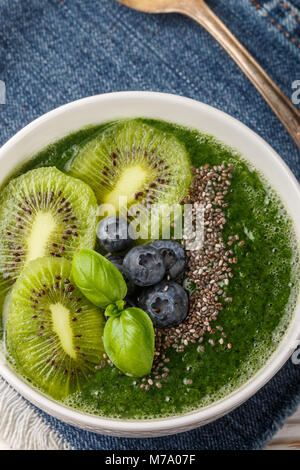 Un sano frullato verde spinaci, banana, avocado, kiwi con semi di Chia e mirtilli. Detox. Una sana prima colazione. Messa a fuoco selettiva Foto Stock