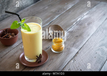 Curcuma Lassie o lassi in vetro - sani indiano probiotici bevanda fredda fatta di cagliata (yogurt), latte, spezie e zucchero. Curcuma Smoothie su legno, Foto Stock