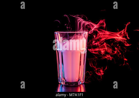 Un vetro trasparente riempita con un cloud da un rosso vape fuma e sorge su un isolato nero lo sfondo Foto Stock