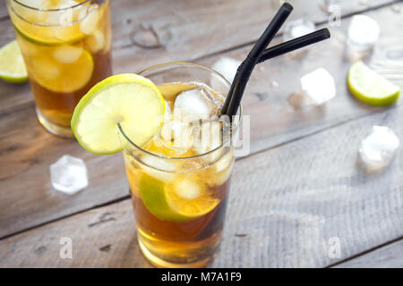 Tè freddo con calce e cubetti di ghiaccio su sfondo di legno, copia dello spazio. Fredda ghiacciata bevanda estiva - Long Island Iced Tea Cocktail. Foto Stock