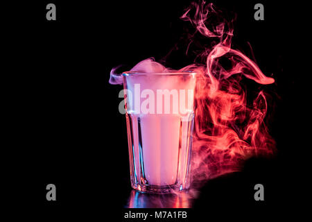 Un vetro trasparente riempita con un cloud da un rosso vape fuma e sorge su un isolato nero lo sfondo Foto Stock