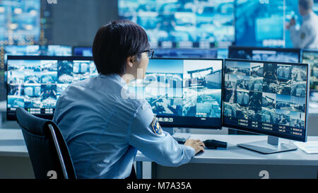 Nella sala di controllo per la sicurezza Officer i monitor di schermi multipli per attività sospette. Egli è circondato da monitor e le protezioni importante impianto Foto Stock