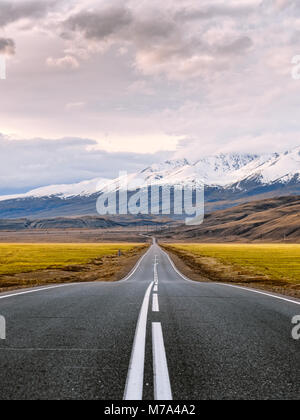 Invitante strada di montagna. Dritto strada pavimentata con superficie bianca iscrizioni passa attraverso le montagne innevate di Altai Repubblica, Russia. Foto Stock