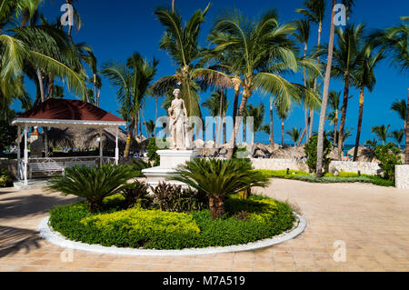 Un stile Greco statua e rifugio sono situati tra le palme, in una giornata di sole in spiaggia con belle blue skies. Foto Stock