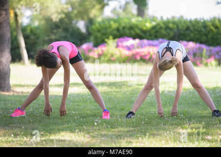 Due donne stretching adduttori lunghi di riscaldamento prima di eseguire Foto Stock