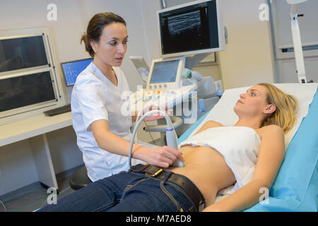 Giovani donne medico lo spostamento del trasduttore a ultrasuoni sul ventre womans Foto Stock