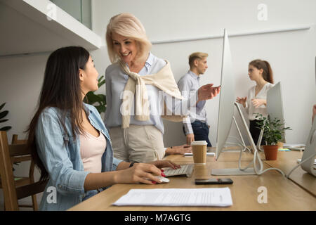 Sorridendo felice di senior executive parlando di asian dipendente al lavoro Foto Stock