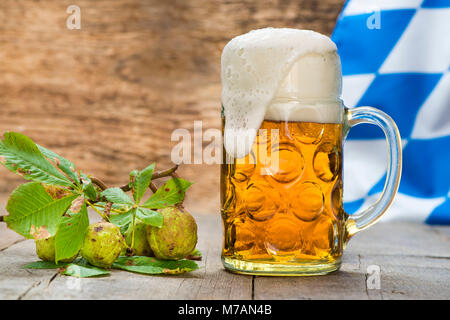 Boccale di birra con la birra in Baviera con castagne e bandiera bavarese in bianco-blu Foto Stock