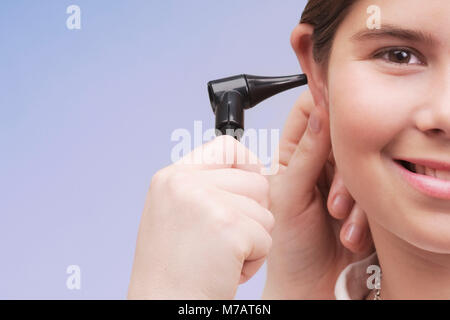 Medico donna esaminando una ragazza orecchio con un otoscopio Foto Stock