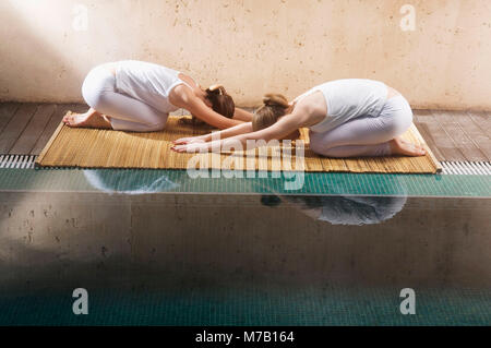 Profilo laterale di due giovani donne che esercitano presso la piscina Foto Stock