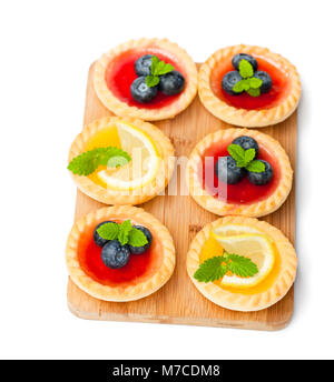 Set di gustose tortine con limone e confettura di lamponi sulla tavola di legno isolato Foto Stock