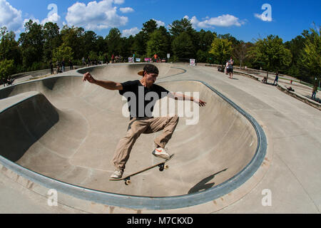 Un giovane uomo esegue un midair skateboard trick in skateboard di coppa a ponte si assesta Park in Suwanee GA, 16 settembre, 2017. Foto Stock