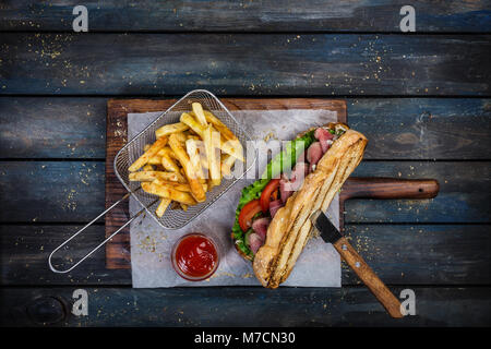 Grandi sandwich di pane con verdure e arrosto di manzo sul tagliere di legno Foto Stock