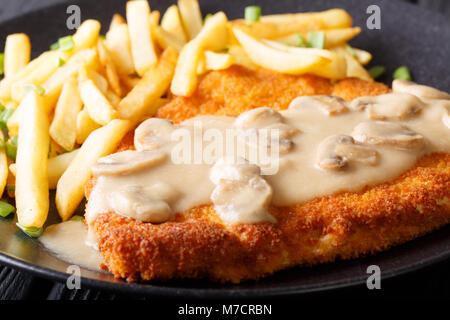 Jaeger schnitzel con patatine fritte e funghi close-up su una piastra orizzontale. Foto Stock