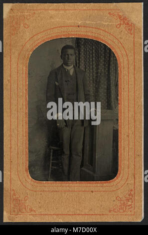 Questo ritratto a figura intera raffigura un giovane afroamericano in piedi accanto a uno sgabello. L'immagine è una rappresentazione significativa dell'identità afroamericana, evidenziando la rappresentazione culturale. Foto Stock