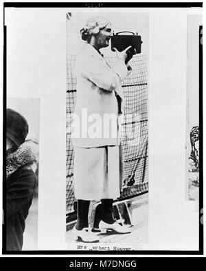 Un ritratto a figura intera della signora Herbert Hoover, membro della White House News Photographers Association, che tiene una macchina fotografica sul suo volto. È rivolta a sinistra nella fotografia. Foto Stock