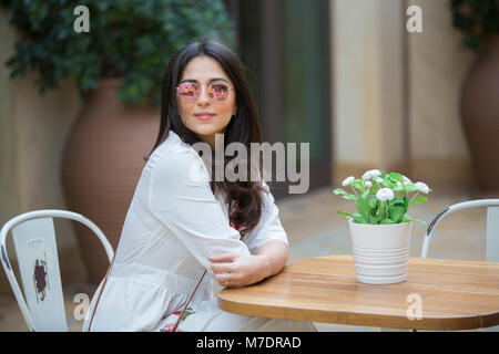 Bella donna che indossa gli occhiali da sole seduti in un caffè a Madinat Jumeirah Souk Dubai EMIRATI ARABI UNITI Foto Stock