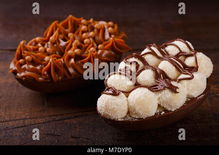 Uovo di cioccolato con ripieno di Pasqua su sfondo di legno. Messa a fuoco selettiva Foto Stock