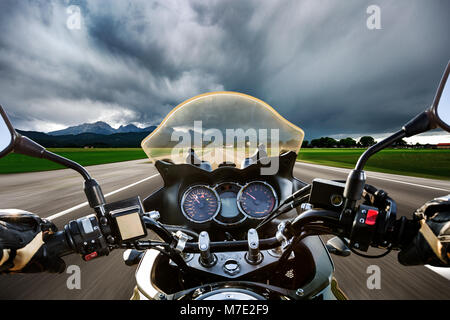 Biker su un motociclo lanciarsi giù per la strada in un fulmine storm - Forggensee e Schwangau, Germania Baviera Foto Stock
