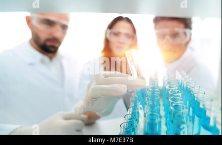 Immagine di sfondo è un gruppo di scienziati che studiano il liquido nel tubo di vetro. Foto Stock