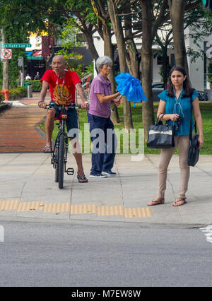 Un uomo sulla sua bicicletta e due donne in attesa ad un semaforo. Foto Stock