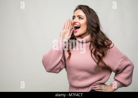 Giovane donna gridare e urlare usando le sue mani come un tubo, studio shoot isolati su sfondo bianco Foto Stock