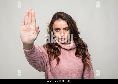 Ritratto di una donna in piedi con la mano tesa che mostra il gesto di arresto isolate su sfondo bianco Foto Stock