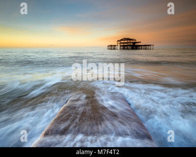 Acqua correndo su un molo di pietra presso il molo vecchio, Brighton. Foto Stock