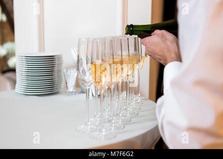 Cameriere versa dello Champagne. fila di bicchieri alla celebrazione Foto Stock