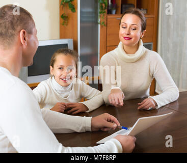 Genitore e sorridente piccolo figlia di rispondere a domande di outreach lavoratore a casa Foto Stock