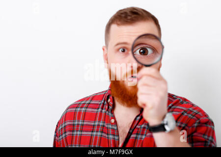 Uomo Barbuto guardando alla lente di ingrandimento Foto Stock