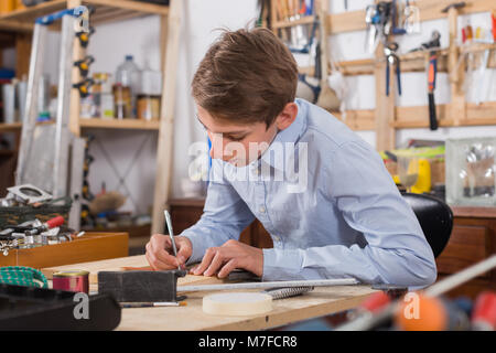 Allegro adolescente europea sorridente e la lavorazione del legno in officina Foto Stock