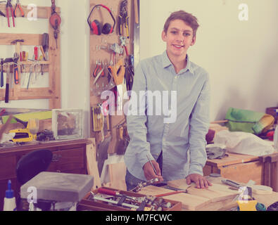 Allegro spagnolo adolescente sorridente e la lavorazione del legno in officina Foto Stock