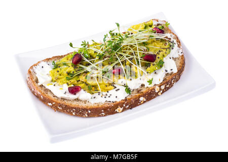 Tutto il pane di grano con avocado, verde i germogli e i semi di melograno Foto Stock