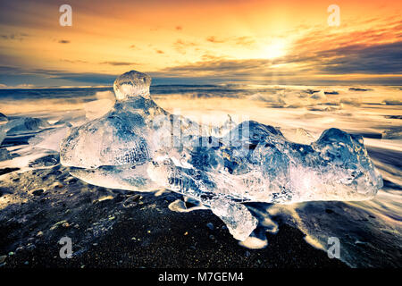 Vaganti iceberg sulla spiaggia di diamante, al tramonto, in Jokulsarlon, Islanda. Foto Stock