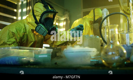 In metropolitana farmaco due laboratori chimici clandestino indossando maschere protettive e tute cotta di prova della droga di purezza e di potenza. Foto Stock