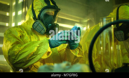 In metropolitana farmaco Laboratorio Chimico clandestino di indossare la maschera protettiva e tuta detiene il sacchetto con Blue met anfetamina. Foto Stock