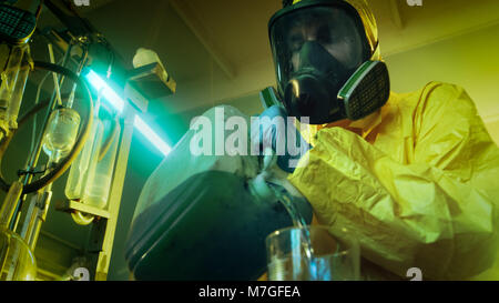 In metropolitana farmaco Laboratorio Chimico clandestino di indossare la maschera protettiva e tuta miscele di sostanze chimiche. Egli versa il liquido dal contenitore. Foto Stock