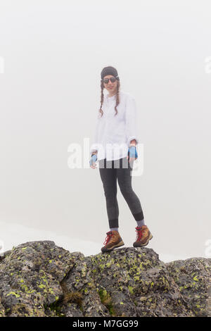 Donna turistiche a piedi lungo un terreno roccioso nella nebbia meteo. Stile di vita la vacanza estiva per natura, il concetto di avventura all'aperto, Escursionismo e trave Foto Stock