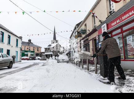 ATHENRY, Irlanda - MARZO 02: uomo non identificato un raschiamento neve a fronte della piazza Inn pub durante la tempesta Emma su Marzo 02, 2018 in Athenry, IRELA Foto Stock