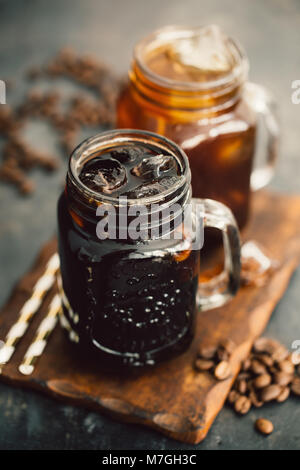 Due vasi con diversi dark drink rinfrescanti serviti sulla tavola di legno. Foto Stock